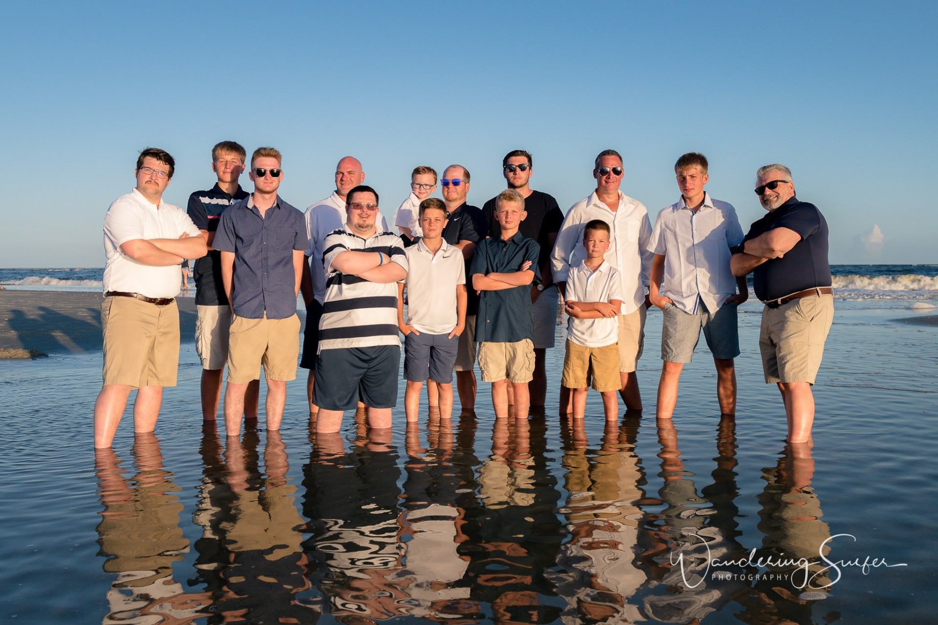 Large family group standing together in shallow ocean water on the beach